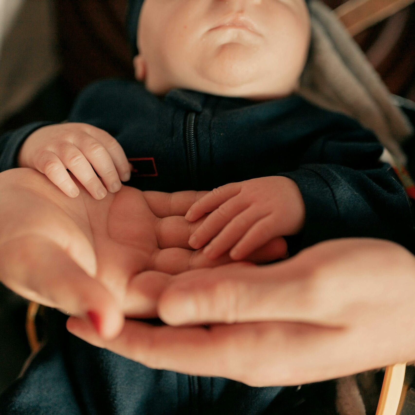 Close-up of parents holding their baby's hands, symbolizing love and protection.